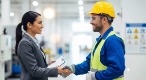 Representante do RH cumprimenta técnico em segurança do trabalho, realizando gestão SST conjunta